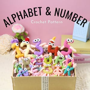 Può includere: Una scatola di cartone piena di lettere e numeri dell'alfabeto all'uncinetto colorati, ognuno con occhi mobili. Il testo "ALPHABET & NUMBER Crochet Pattern" è visualizzato sopra la scatola su uno sfondo rosa.