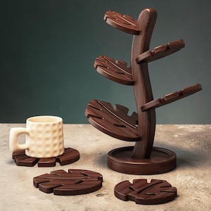 May include: A wooden mug tree with leaf-shaped shelves and matching coasters. The tree is dark brown, and the coasters and mug base have a similar leaf design. A beige textured mug sits on one of the coasters.