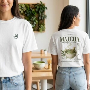 May include: Two white t-shirts with matcha designs. One has a small green matcha bowl logo on the front. The other features a matcha bowl with a whisk, the word "Matcha", and the phrase "Mindful moments" on the back.