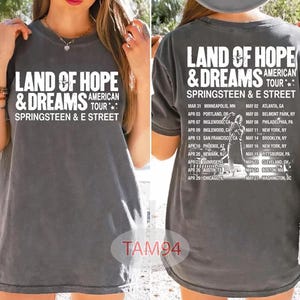 Puede incluir: Camiseta gris con el texto blanco "LAND OF HOPE & DREAMS AMERICAN TOUR SPRINGSTEEN & E STREET". La parte trasera muestra fechas y lugares de la gira. Una camiseta de concierto unisex casual.