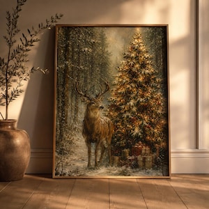 May include: A framed wall art print depicting a snowy forest scene with a large stag standing beside a glowing, illuminated Christmas tree. The tree is decorated with warm lights and dusted with snow, with several wrapped gift boxes at its base.