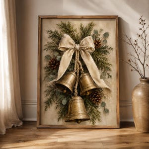 May include: A framed wall art print featuring a painting of three metallic gold bells hanging from a large, light beige fabric bow. The bells are nestled among green pine branches, eucalyptus leaves, and brown pinecones on a neutral background.