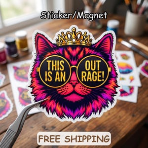 May include: A sticker or magnet featuring a stylized cat with vibrant pink and purple fur, wearing a gold crown and round black sunglasses. The lenses of the glasses display the yellow text THIS IS AN OUT RAGE! in a bold, capitalized font.
