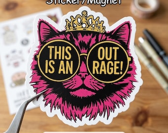 May include: A sticker or magnet featuring a pink and black cat wearing sunglasses and a gold crown. The text on the glasses reads "THIS IS AN OUT RAGE!". The sticker is on a wooden surface.
