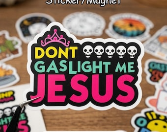 May include: A sticker or magnet with the text "DON'T GASLIGHT ME JESUS" in yellow, teal, and pink, with skull graphics. The sticker has a black border and a pink crown graphic. Other stickers are in the background.