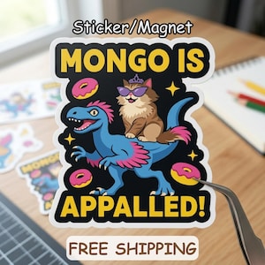 May include: A sticker or magnet featuring a cartoon illustration. A blue dinosaur with pink accents carries a cat wearing sunglasses and a crown. The text reads "MONGO IS APPALLED!" with donut and star graphics.