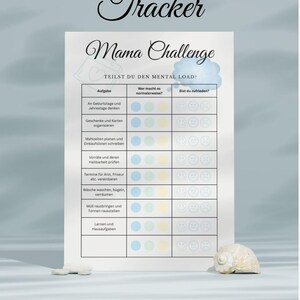 May include: A white printable "Mental Load Tracker" chart with the title "Mama Challenge" in a decorative font. The chart includes sections for tasks, who does them, and satisfaction levels. A seashell and small stone are at the bottom.