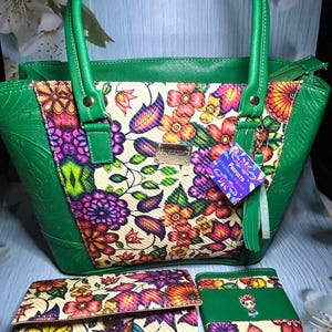 Puede incluir: Un bolso verde con paneles estampados florales, cartera y tarjetero a juego. El bolso tiene asas y ribetes verdes, con un colorido estampado floral en la parte delantera. La cartera y el tarjetero presentan el mismo diseño floral.