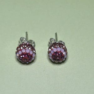 A pair of earrings with purple and pink gemstones, possibly diamonds, set in a silver-colored metal.