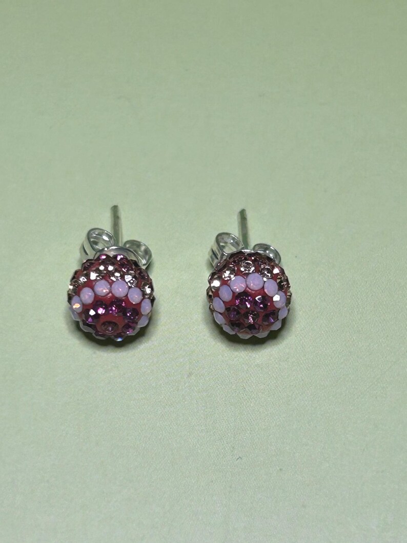 A pair of earrings with purple and pink gemstones, possibly diamonds, set in a silver-colored metal.