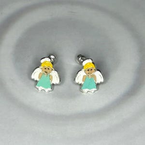A pair of silver earrings with small, cartoon-like figures of angels on a gray background.