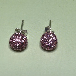 A pair of purple glitter earrings with a round, spherical design.