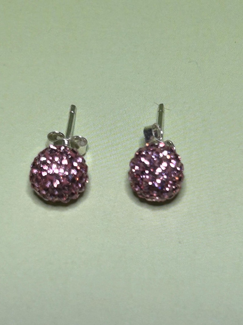 A pair of purple glitter earrings with a round, spherical design.