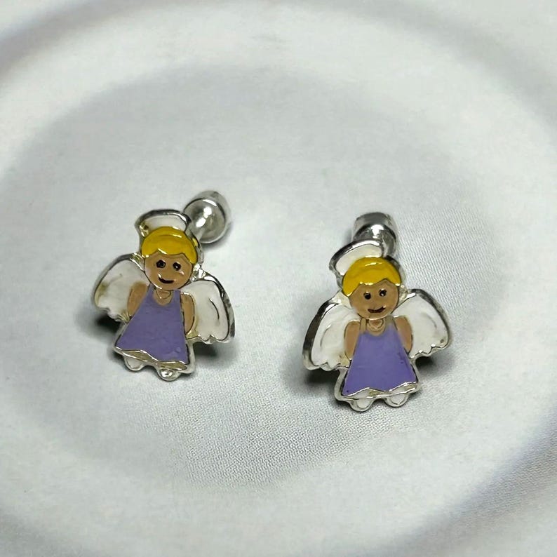 A pair of silver earrings with cartoon-like angel designs on a white background.