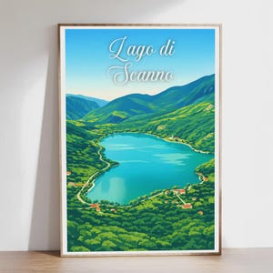 Può includere: Stampa artistica incorniciata con una vista panoramica del Lago di Scanno, Italia. L'opera raffigura un lago turchese circondato da verdi colline e montagne sotto un cielo azzurro. Il testo "Lago di Scanno" è visualizzato in una scrittura elegante.