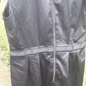 May include: A black sleeveless dress with a zipper down the back and a band around the waist.