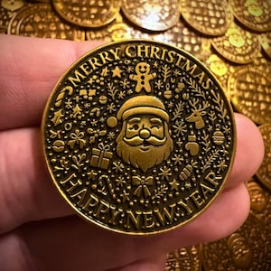 Puede incluir: Una moneda navideña dorada con las palabras "MERRY CHRISTMAS" y "HAPPY NEW YEAR" grabadas alrededor del borde. La moneda presenta la cara de Papá Noel, copos de nieve y otros símbolos festivos.