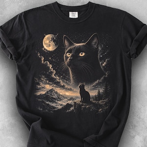 May include: Black t-shirt with a detailed illustration of a black cat with yellow eyes looking at a full moon. A smaller cat silhouette sits on a cliff overlooking a mountain landscape. The word "BLACK" is printed at the bottom.