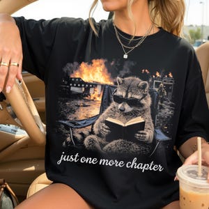 May include: A white ceramic mug with a black handle and the text "But First, Coffee" in a bold, black font. The mug is set against a blurred background, suggesting a cozy setting.