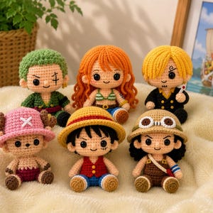 May include: A collection of six crocheted dolls, each representing a character with distinct features. The dolls have various hair colors, outfits, and accessories, including hats and a small cigarette. The dolls are arranged on a soft, white surface.