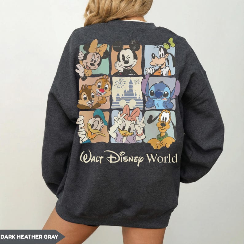 Może przedstawiać: Ciemnoszara bluza z nadrukiem przedstawiającym postacie Disneya, w tym Myszka Miki i Stitch. Poniżej nadruk z napisem "Walt Disney World". Styl casualowy i wygodny.