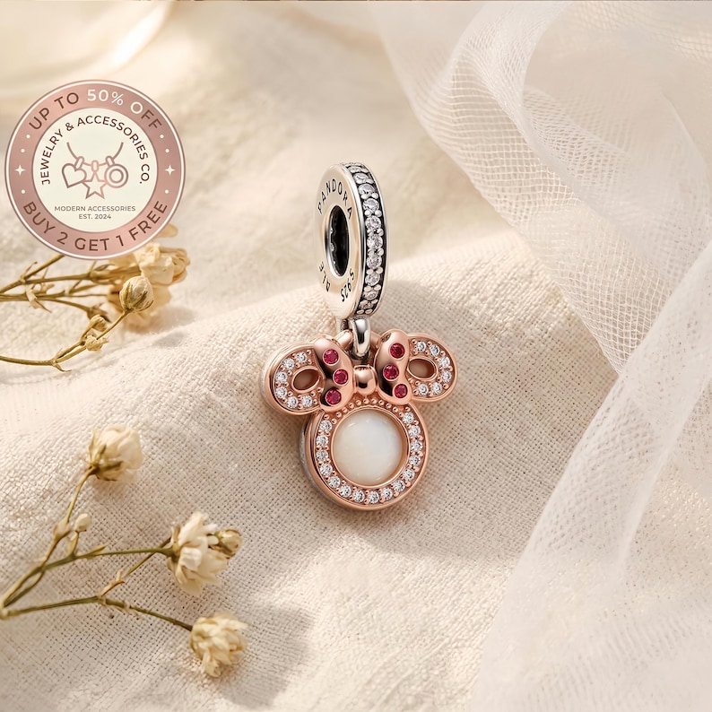 Puede incluir: Un charm en tono oro rosa con una piedra central blanca circular rodeada de circonitas transparentes, rematado con un lazo con piedras rosas. El pasador est&aacute; grabado con PANDORA y S925, con una hilera de piedras transparentes en el borde.
