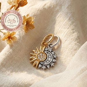 Puede incluir: Un colgante dorado y plateado con un diseño de sol y luna. El sol es dorado con un grupo central de pequeñas piedras transparentes. La luna es plateada con piedras transparentes. El colgante tiene un lazo para una cadena. El texto "UP TO 50% OFF" y "BUY 2 GET 1 FREE" también es visible.