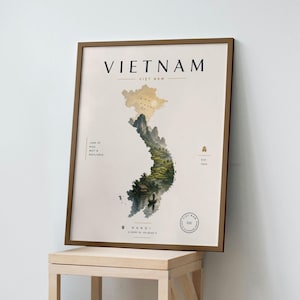 May include: A framed wall art print featuring a map of Vietnam in the shape of the country, filled with a landscape illustration of mountains, rice terraces, and a boat. The text reads VIET NAM, LAND OF RICE, MIST & RESILIENCE, EST 1945, and HANOI.