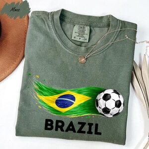 A green t-shirt with a graphic design of the Brazilian flag and a soccer ball, along with the word "BRAZIL" printed on it.