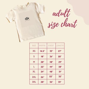 a white t-shirt with a size chart below it, providing measurements for different sizes.
