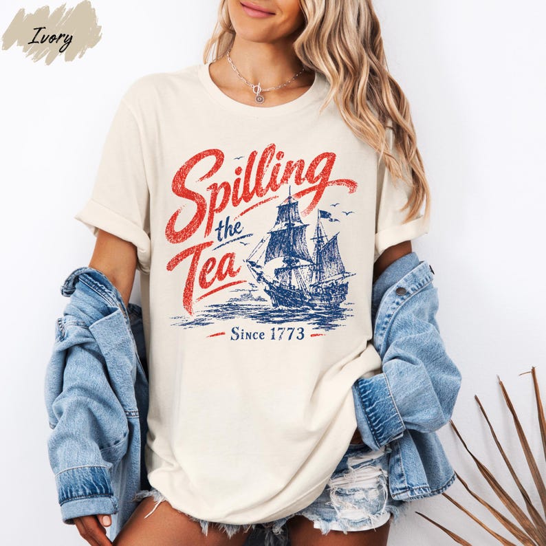A woman wearing a white t-shirt with a graphic design of a ship and the text "Spilling the Tea Since 1773" printed on it.