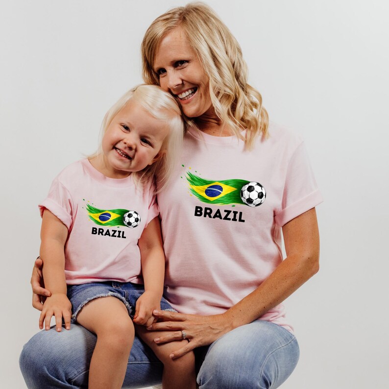 A smiling woman and a young girl wearing matching pink t-shirts with the word "BRAZIL" printed on them.