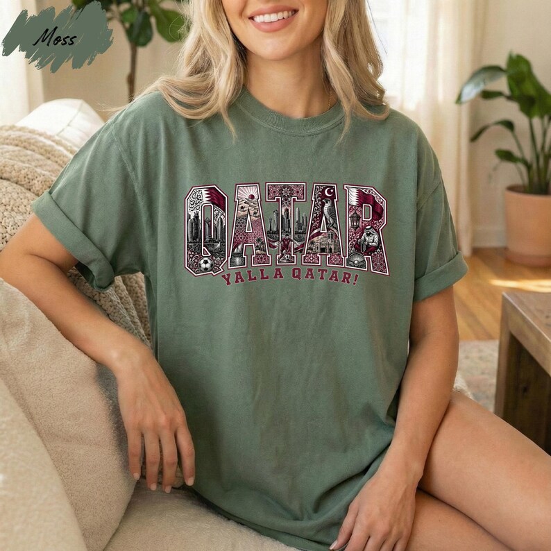 A woman wearing a green t-shirt with the word "Qatar" printed on it, sitting on a couch.