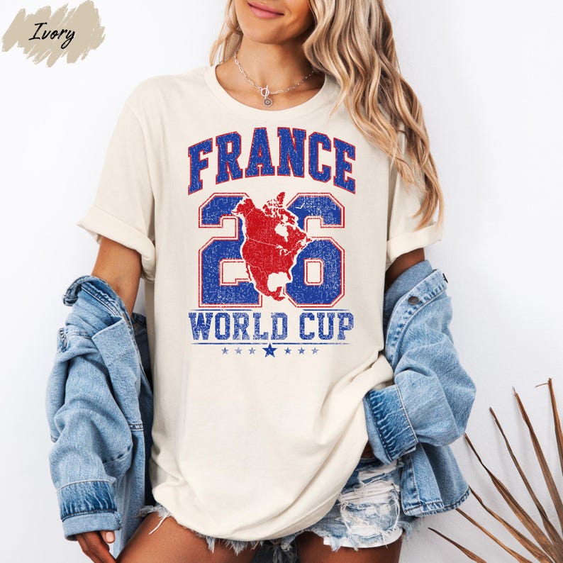 A woman wearing a white t-shirt with the text "FRANCE WORLD CUP" printed on it, along with a graphic of a map and a red and blue design. She is also wearing a denim jacket and denim shorts.