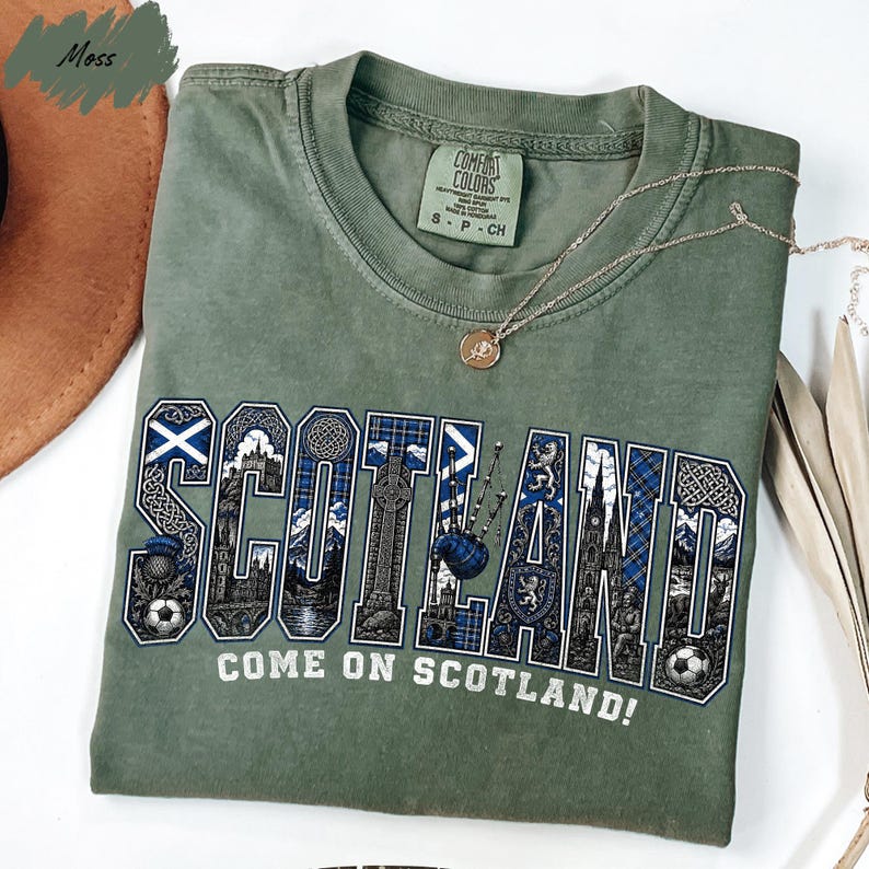 A green t-shirt with the word "SCOTLAND" printed on it, along with various Scottish-themed graphics and text.