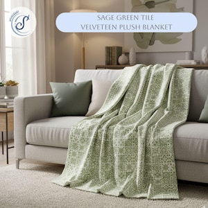 May include: Sage green tile velveeteen plush blanket draped over a light gray sofa. The blanket features a repeating geometric pattern in shades of green and white. The sofa has two green and one beige pillow. The text "SAGE GREEN TILE VELVETEEN PLUSH BLANKET" is in a light blue banner.