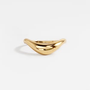 May include: A gold ring with a smooth, curved design. The ring has a polished, reflective surface, and is set against a white background. The ring's shape is reminiscent of a wave or a crescent moon. Jewellery.