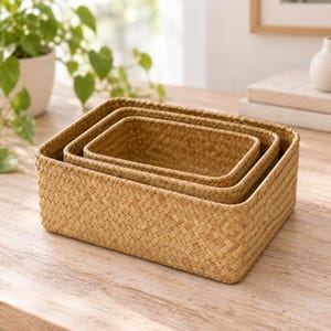 May include: A set of three rectangular storage baskets nested inside one another. Each basket features a light brown, woven texture with a consistent diagonal pattern throughout the sides and base, creating a uniform appearance for organization.
