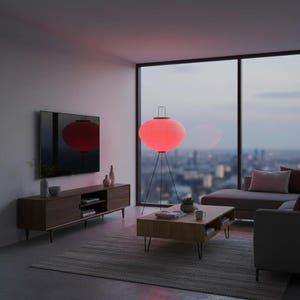 May include: A modern living room with a large, red, illuminated lantern-style floor lamp. The lamp has a tripod base and a spherical shade. A wooden media console, a coffee table, and a gray sofa are also visible. The room has a large window with a city view.