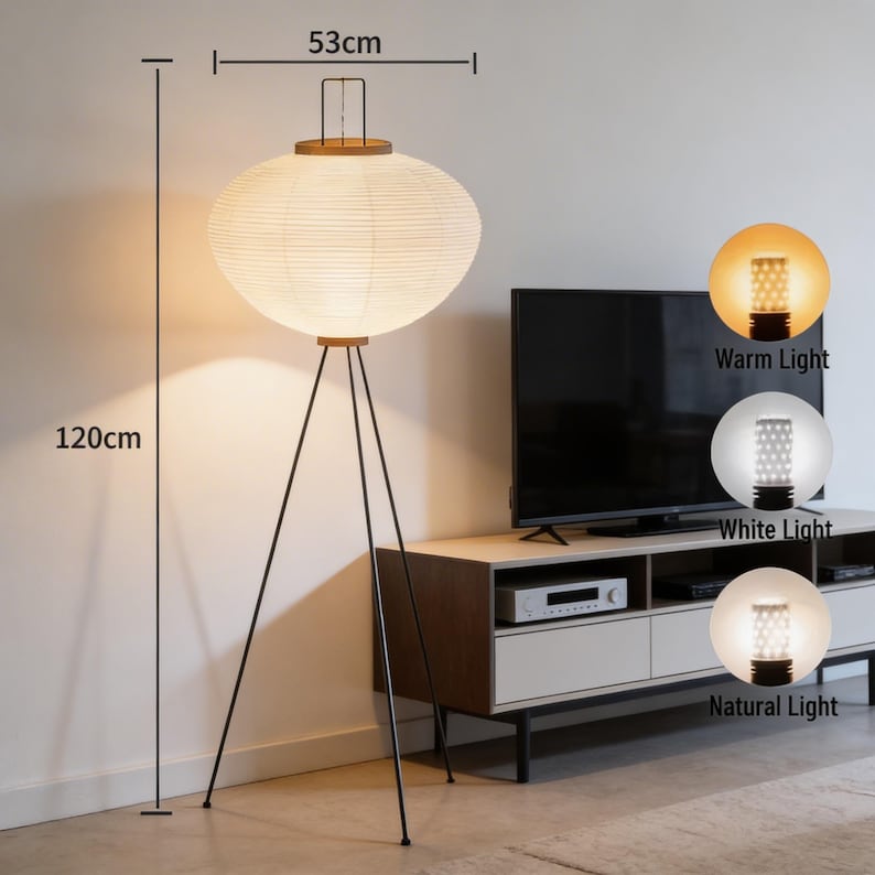 May include: A modern floor lamp with a white paper lantern shade, 120cm tall and 53cm wide, supported by a black tripod base. The lamp has a wooden top and is shown with warm, white, and natural light options.