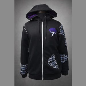 Pode incluir: Casaco com capuz preto com zíper e capuz forrado a roxo. Apresenta um patch de nuvem roxa e raio, e patches xadrez. Costuras brancas acentuam o design. O casaco tem um zíper de comprimento total e um capuz com cordão.