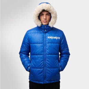 Puede incluir: Chaqueta acolchada azul brillante con capucha ribeteada de piel. La chaqueta presenta el texto "VENGEANCE78" en blanco en el pecho. Tiene un diseño acolchado y un cuello alto, ofreciendo calidez y estilo.