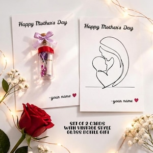 May include: A Mother's Day gift set featuring two cards and a vintage-style glass bottle. One card has a line drawing of a mother and child, the other has a bottle with a purple bow. A red rose and fairy lights complete the scene.