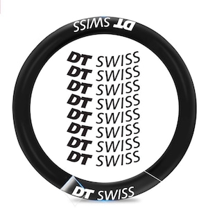 Puede incluir: Llanta de rueda de bicicleta negra con texto blanco "DT SWISS". El texto se repite varias veces alrededor de la llanta. El nombre de la marca también está impreso en blanco.