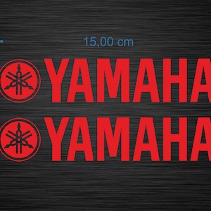 Peut inclure: Deux autocollants rouges avec le logo Yamaha. Chaque autocollant comprend le mot-symbole Yamaha et un emblème circulaire. Les autocollants mesurent 15,00 cm de large et 2,96 cm de haut, sur un fond sombre et texturé.