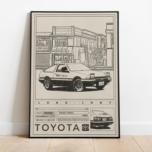 May include: Black and white illustration of a Toyota AE86 car with a Japanese street scene background. The poster includes the years 1983-1987 and the Toyota logo. The poster is framed in a black frame.