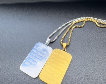 May include: Two rectangular pendant necklaces. One is silver-toned, the other gold-toned. Both pendants have etched text and hang from matching chain necklaces. The pendants are displayed on a dark surface.