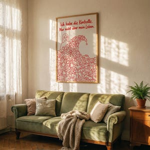 Könnte beinhalten: Ein gerahmter Kunstdruck mit dem Text "Ich habe die Kontrolle. Nur nicht über mein Leben." in Rot. Das Kunstwerk zeigt eine Person und eine Welle aus roter Linienkunst. Im Vordergrund befindet sich ein grünes Samtsofa mit Kissen und einer Decke.