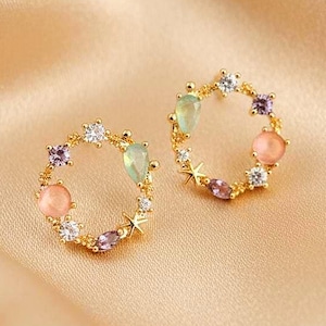 Pendientes de corona floral con diseño circular dorado y circonitas, una joya femenina y delicada.