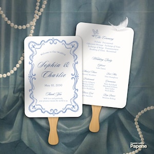 May include: Two white rectangular wedding program fans with wooden handles. The front features a blue decorative border, the names Sophia & Charlie, and the date May 10, 2030. The back lists the ceremony order and wedding party members.